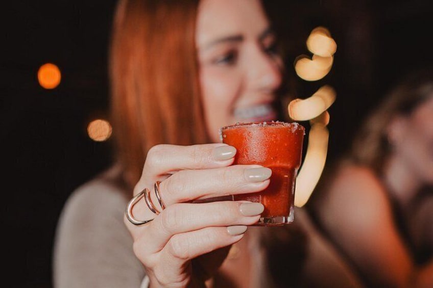 Una persona sosteniendo un vaso con una bebida roja. 2