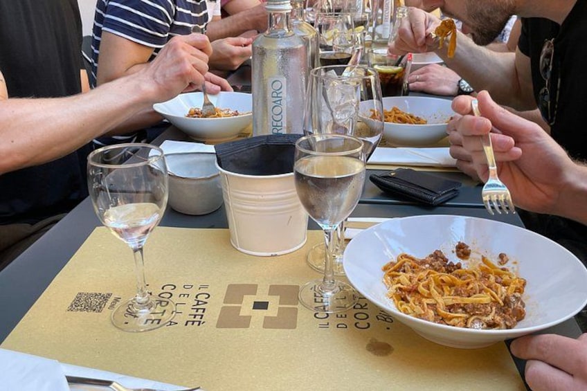 Personas cenando en una mesa con platos de comida y vasos de agua, además de una botella. 3
