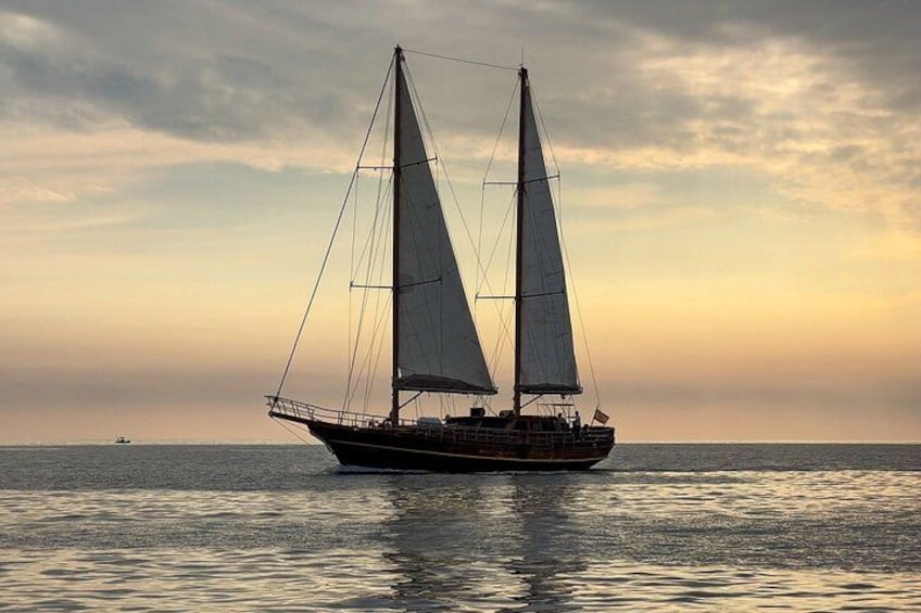 A sailboat with two sails on a calm sea during sunset. 2