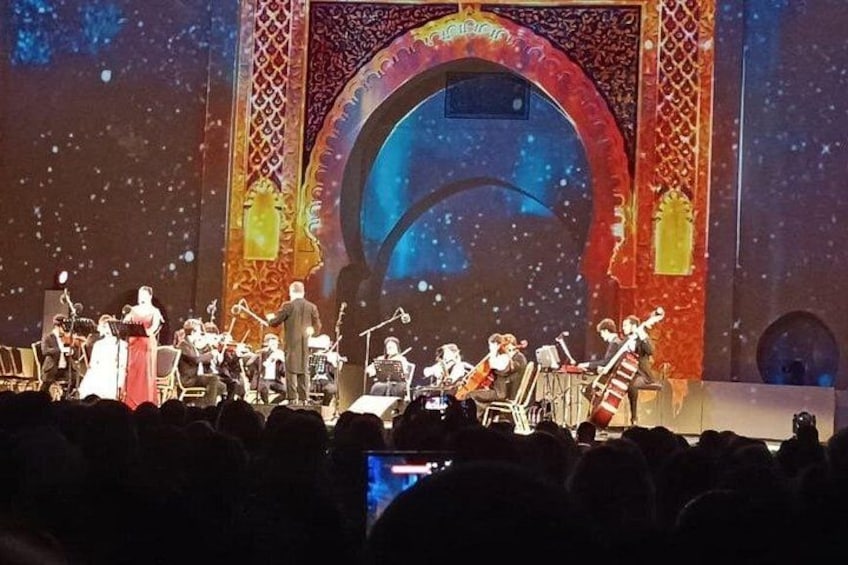 Eine Band tritt auf einer Bühne auf, wobei ein großer Bildschirm einen blauen Hintergrund zeigt. 4