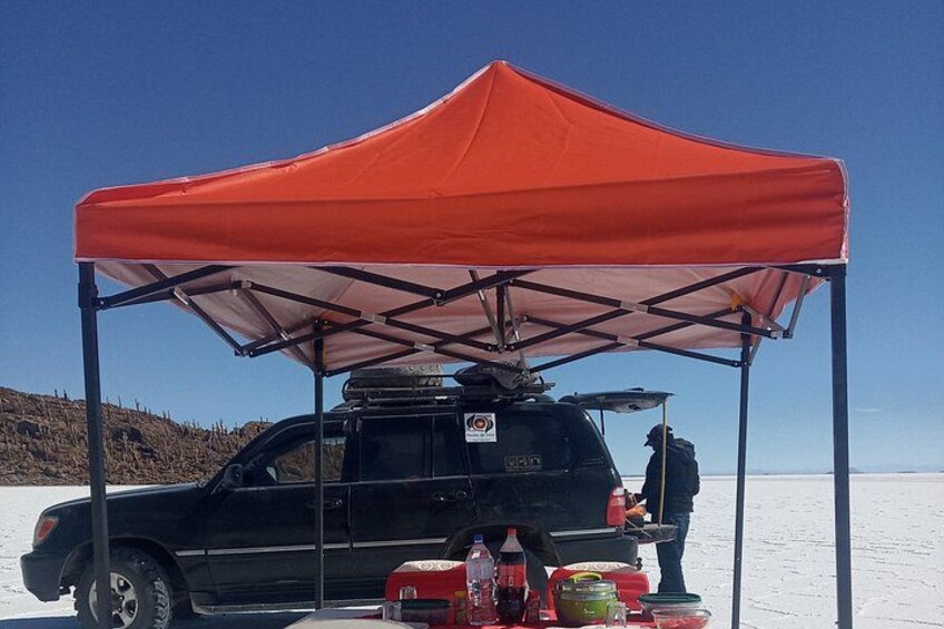 A black SUV parked under a red tent on a snowy landscape. 2