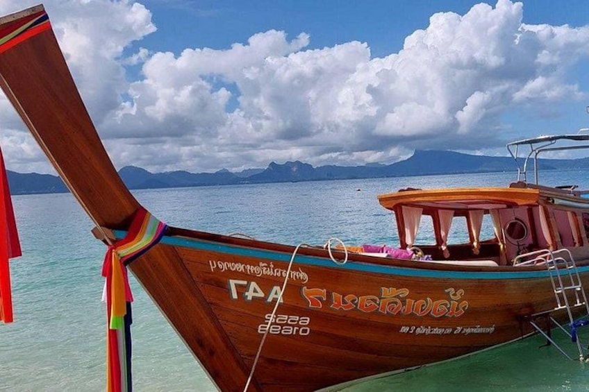 A wooden boat with a colorful tail fin, a cabin, and a person standing on the deck. 3