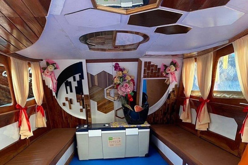 A cabin with wooden walls, a central desk, and decorative floral arrangements. 2