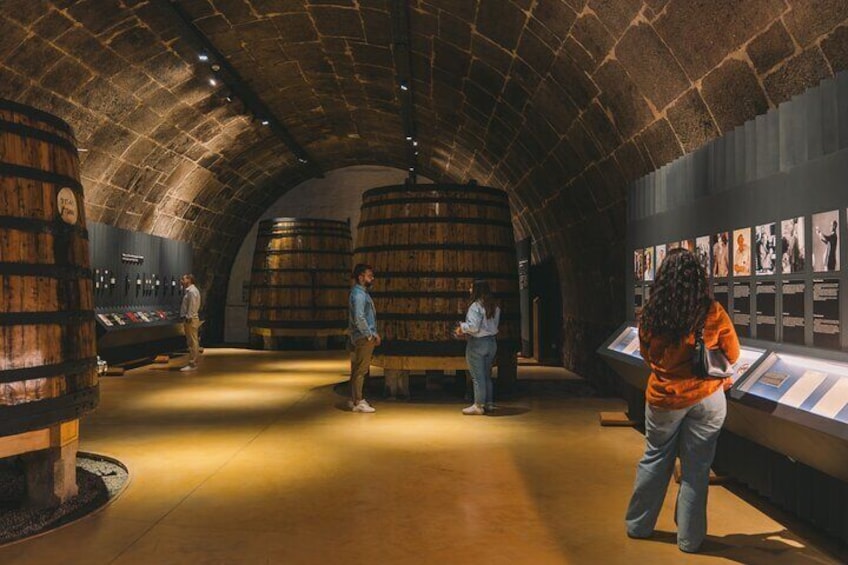 A museum with stone vault ceilings, wooden barrels, and informational displays. 2