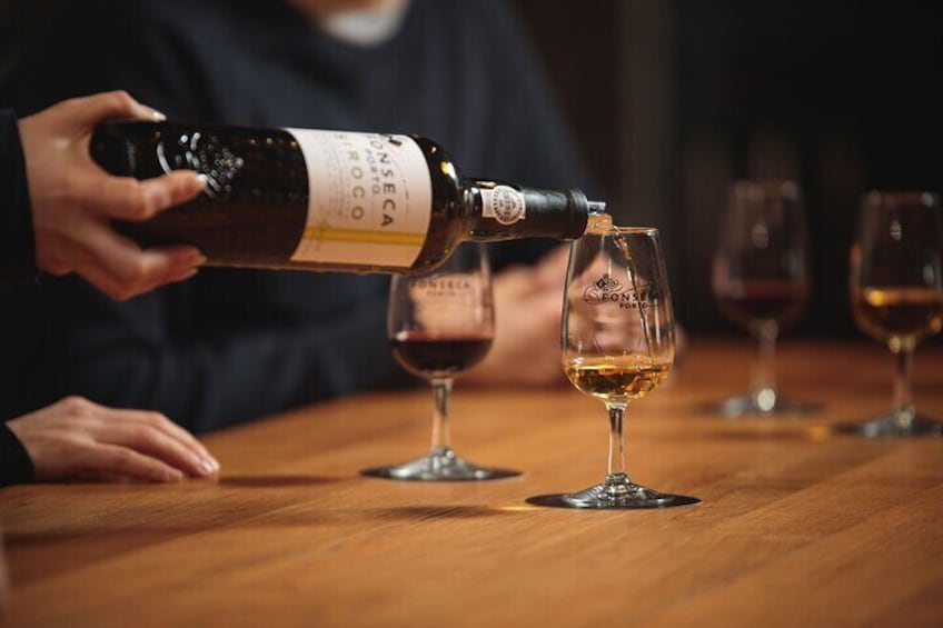 A person pouring wine from a bottle into a glass. 4