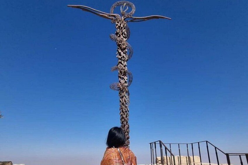 A tall metal sculpture resembling a bull with horns, a person in the foreground, and a clear blue sky. 3