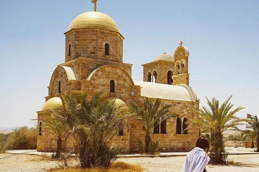 A stone church with a large dome and smaller domes, surrounded by palm trees. 5
