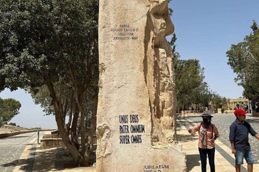 Un monumento de piedra con inscripciones, un árbol y una persona parada cerca. 4