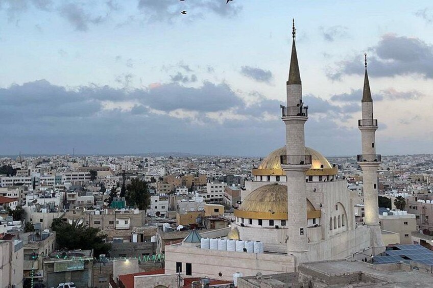 A mosque with two minarets and a golden dome, surrounded by a cityscape. 4