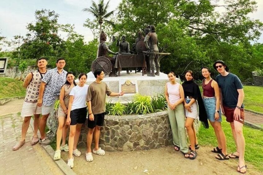 Eine Gruppe von Personen posiert vor einer Statue in einem Park. 3