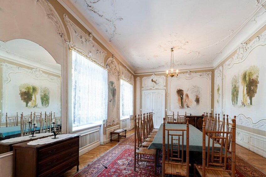 En elegant spisesal med detaljerede vægdekorationer, et langt bord og stole. 4