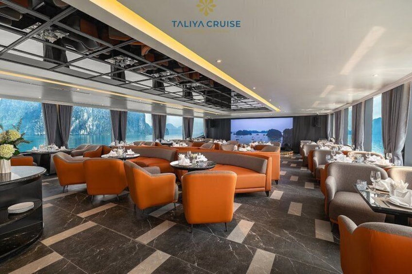 A modern restaurant with orange seating and a large TV screen displaying a scenic view. 5