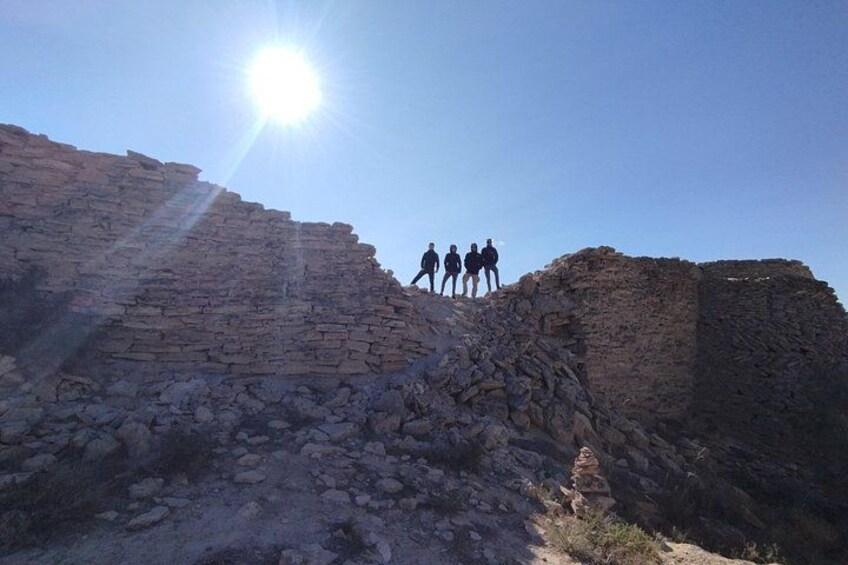 A group of people standing on a rocky hill with the sun shining in the background. 4