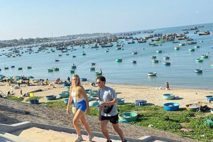 A beach with numerous small boats and people walking along the shore. 4