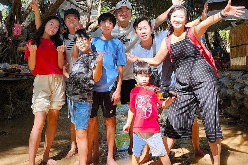 Un grupo de personas de pie al aire libre, algunas con mochilas, en un entorno natural con árboles y un sendero de tierra. 3