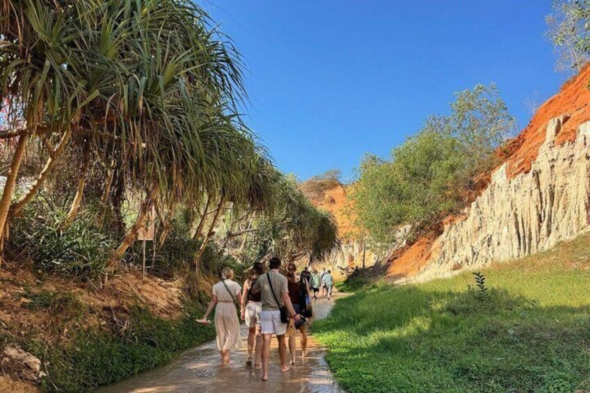 A group of people walking along a path surrounded by greenery and cliffs. 3