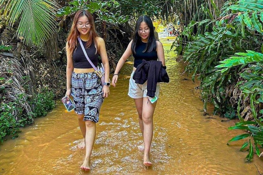Dos personas caminando por un sendero inundado, rodeado de vegetación densa. 5