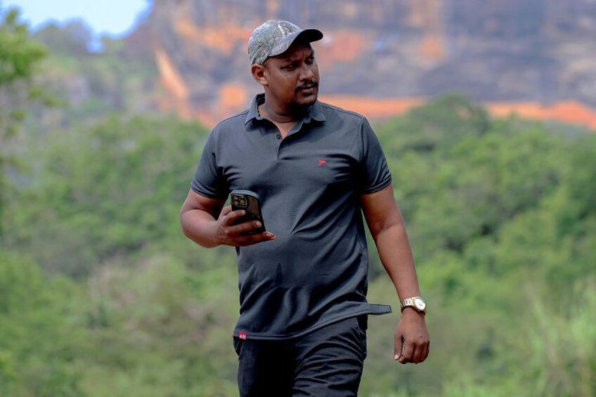 A person walking outdoors with a smartphone, wearing a dark polo shirt and a cap. 4