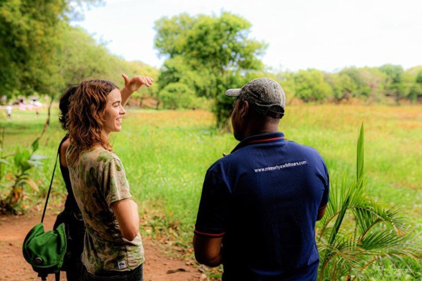 Two people in a field with greenery and trees in the background. 2