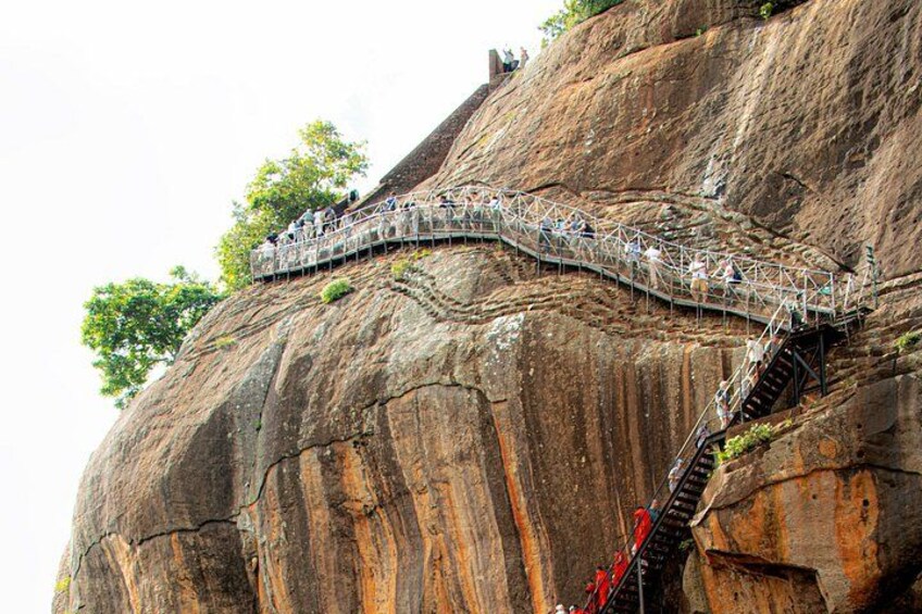 A suspension bridge over a large rock formation with people walking on it. 2