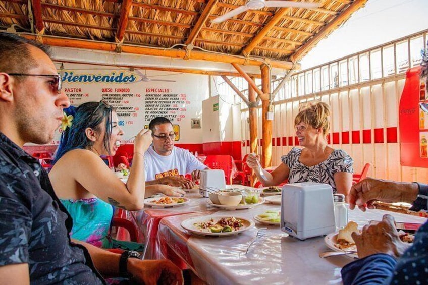 People dining at an outdoor restaurant with a menu board in the background. 5