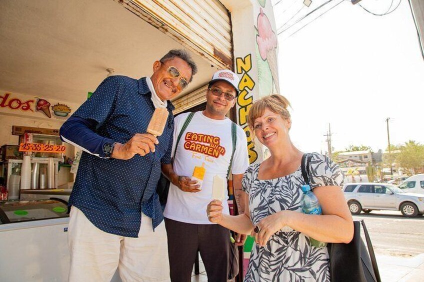 Three people standing in front of a food truck with a sign that reads 'EATING CREAMY.' 2
