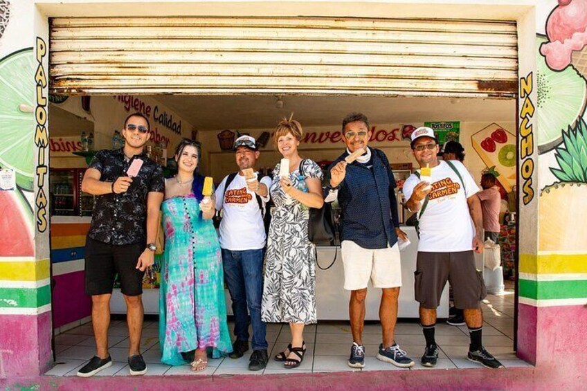 A group of people standing in front of a food stall with a sign that reads 'Nachos.' 4