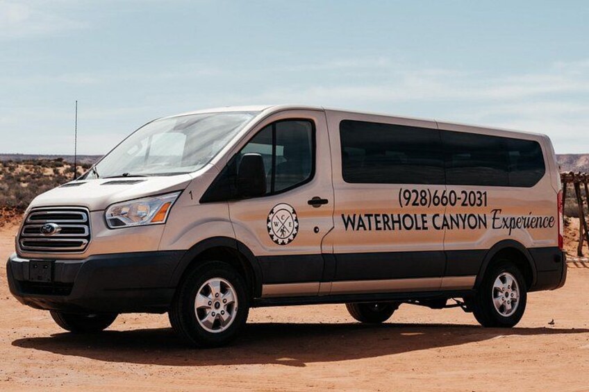 A beige van with 'Waterhole Canyon Experience' and a phone number on its side. 3