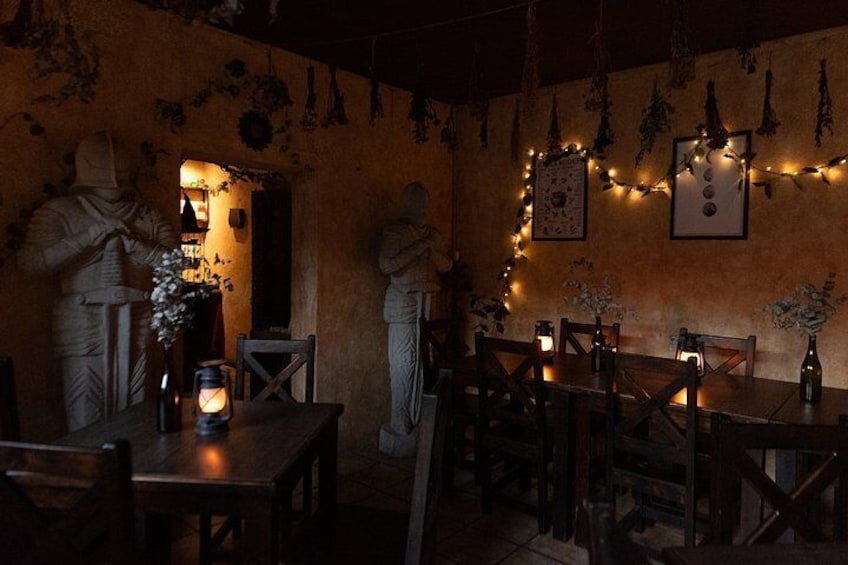 En restaurang med dämpad belysning och rustik inredning, inklusive stenskulpturer och ljusslingor. 4