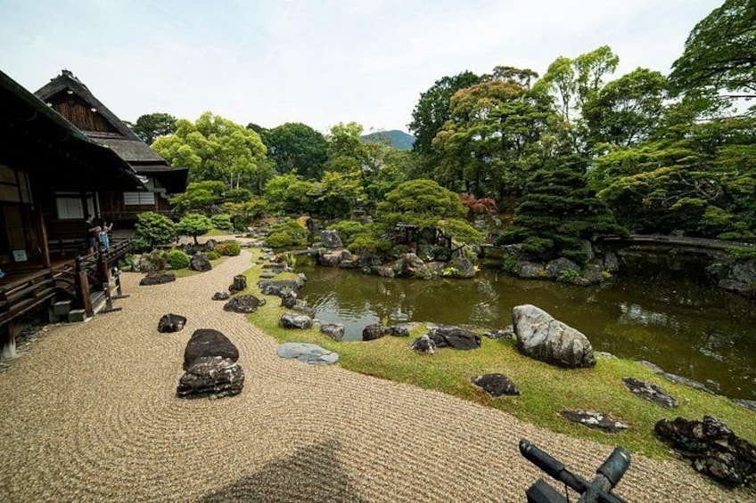 A traditional Japanese garden with a wooden building, a stone path, and a pond. 2