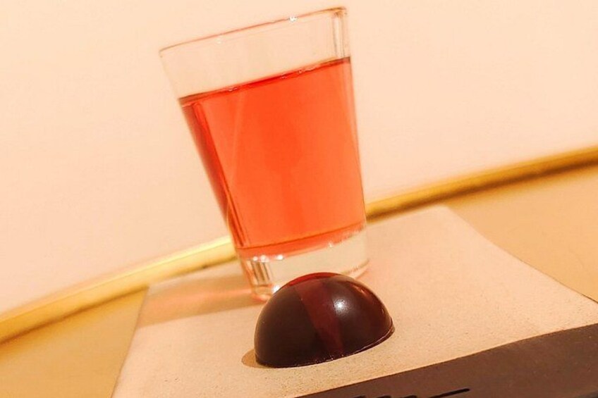 Un vaso de líquido rojo, posiblemente té, sobre un posavasos, con un objeto esférico oscuro a un lado. 3