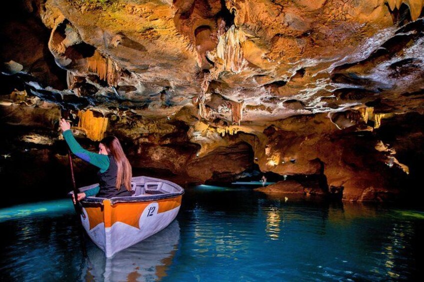 A person in a boat inside a cave with stalactites and stalagmites. 4