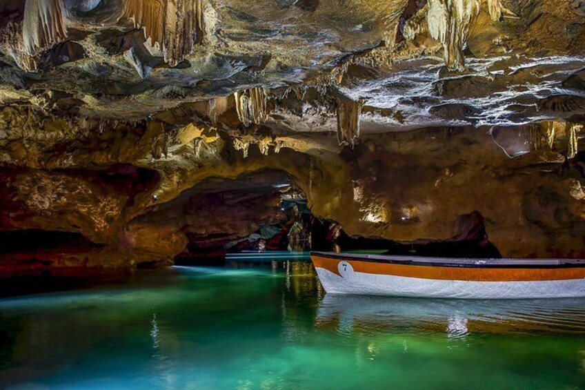 A cave with stalactites, a boat, and a person in a wetsuit. 3