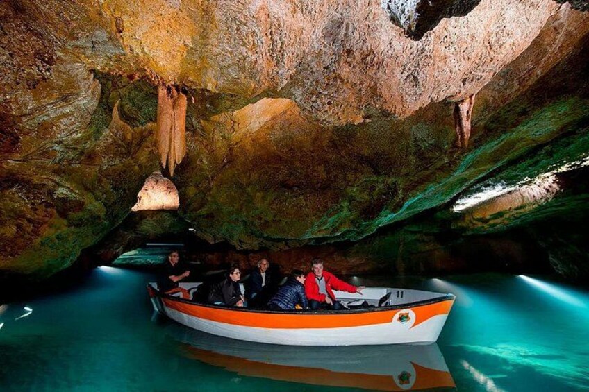 A boat with people inside, surrounded by cave formations and clear water. 1