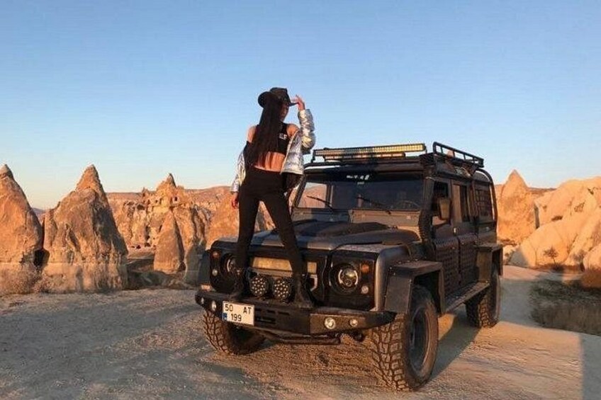 A rugged off-road vehicle parked in a desert landscape with unique rock formations in the background. 4