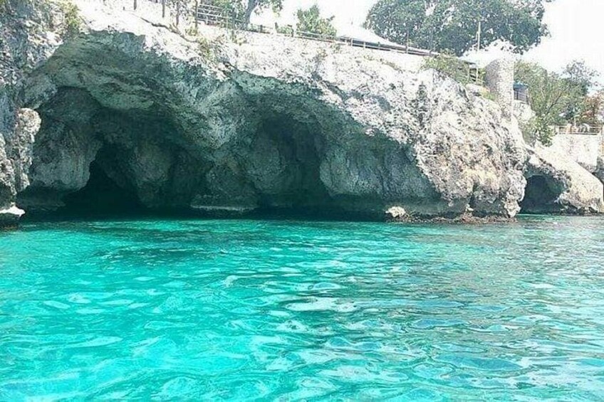 A clear blue sea, a rocky cliff, and a small boat. 3
