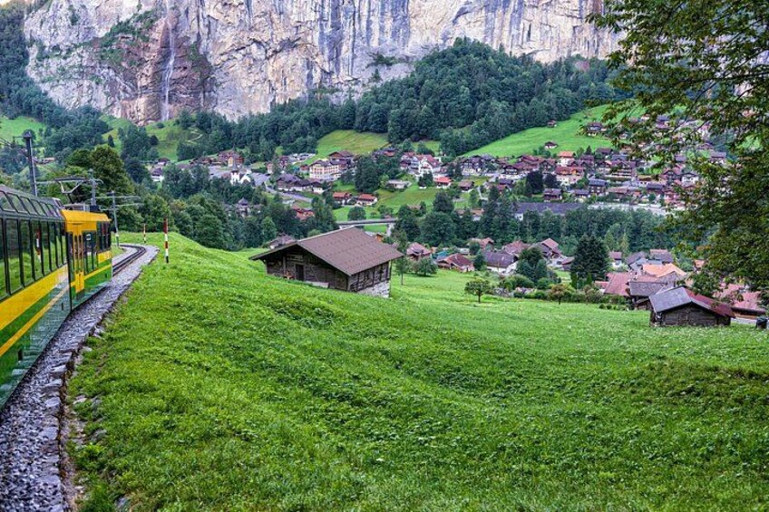 Un tren sobre rieles, un pueblo y montañas al fondo. 2