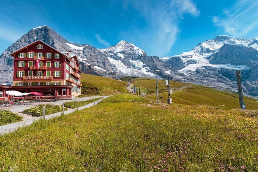Un edificio rojo con un letrero 'DESALPES' en una zona montañosa con picos nevados al fondo. 1