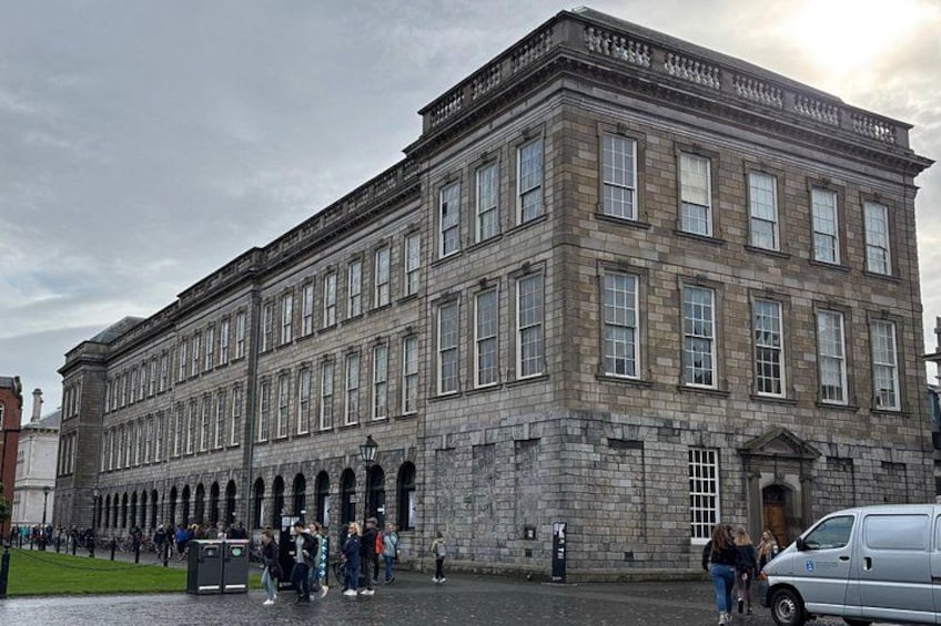 En stor, historisk byggnad i sten med många fönster och en central ingång. 3