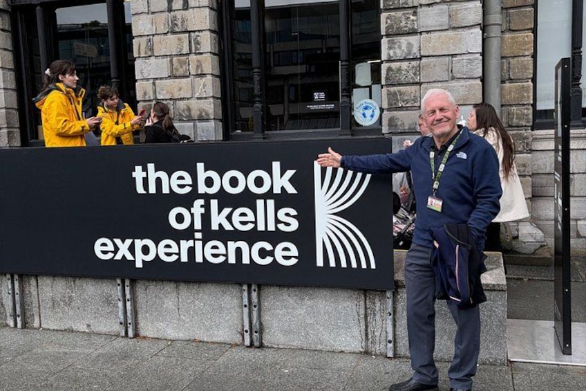 En man står framför en skylt med texten ”upplev Book of Kells”. 5