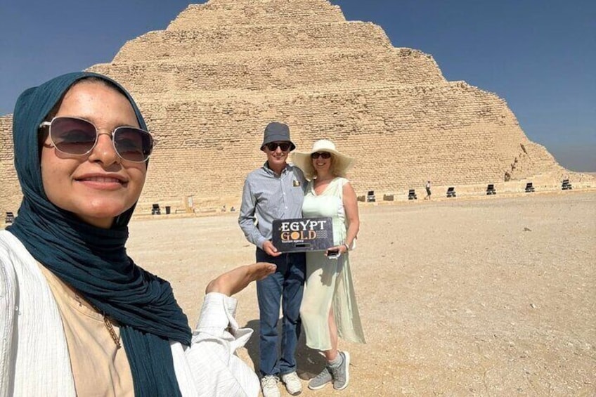 Una gran pirámide al fondo y personas en primer plano sosteniendo un cartel que dice 'EGYPT'. 5