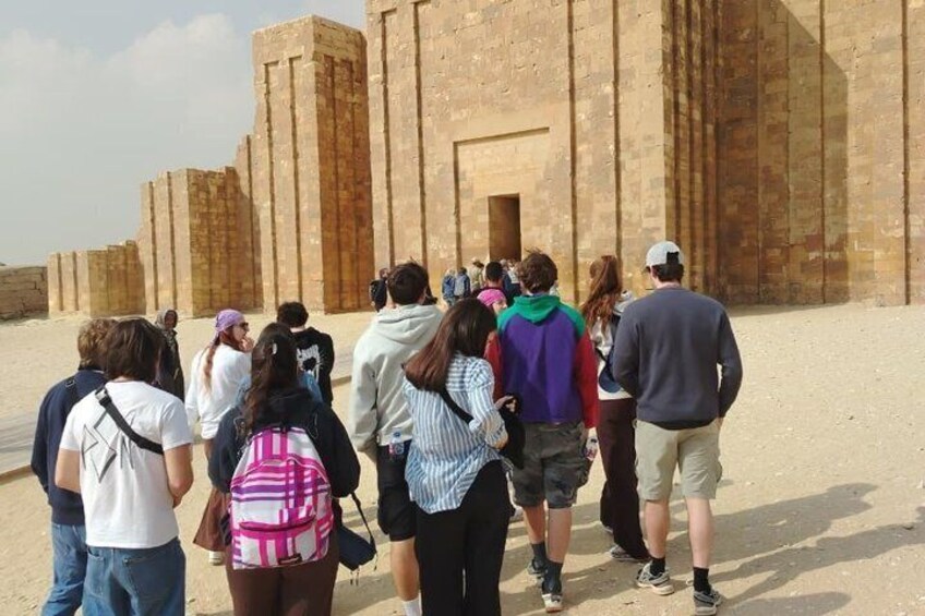 Un grupo de turistas caminando hacia una gran estructura antigua de ladrillo. 3