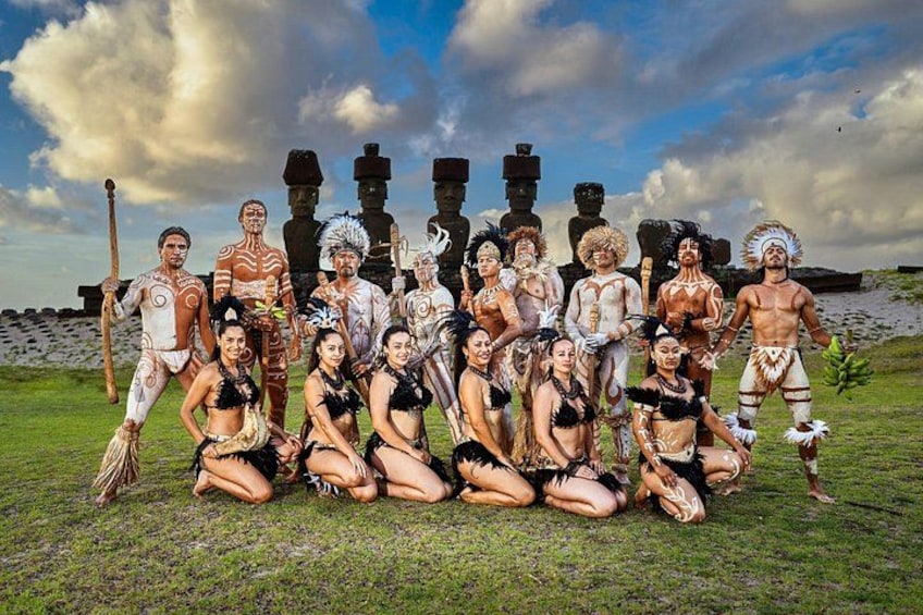 A group of people in traditional attire posing in front of Moai statues. 3