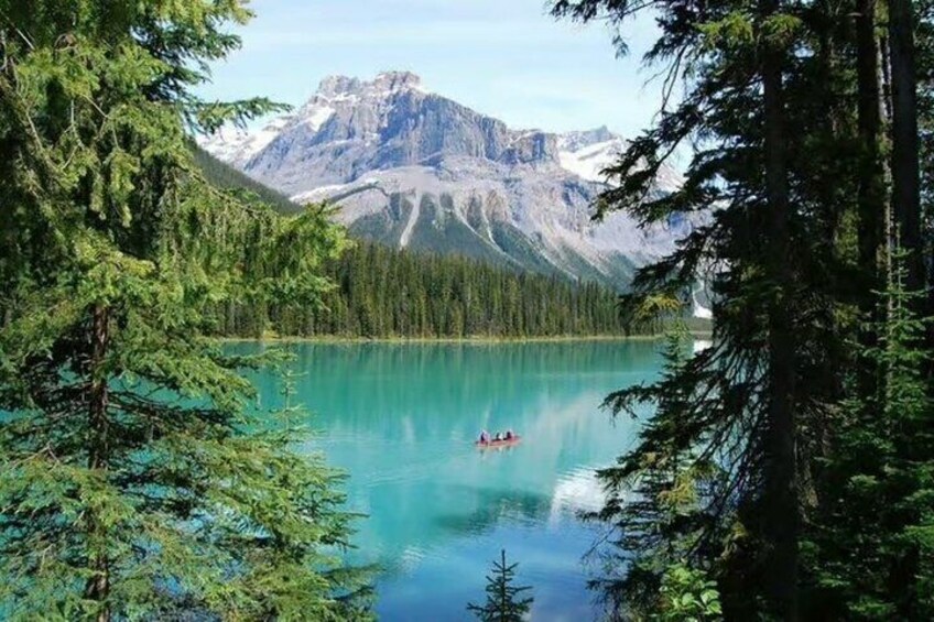 A turquoise lake surrounded by dense forest and mountains. 5