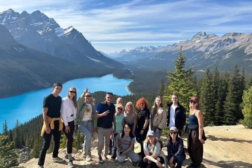 A group of people on a mountain overlooking a lake with mountains in the background. 3