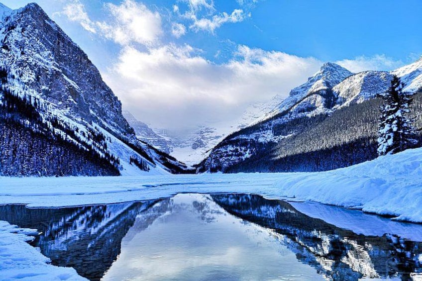 A snow-covered mountain range with a calm lake reflecting the peaks. 4