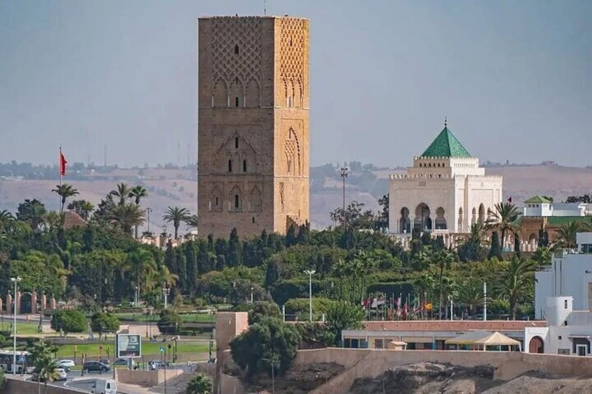 A tall tower with intricate patterns, a mosque with a green dome, and palm trees in the foreground. 4