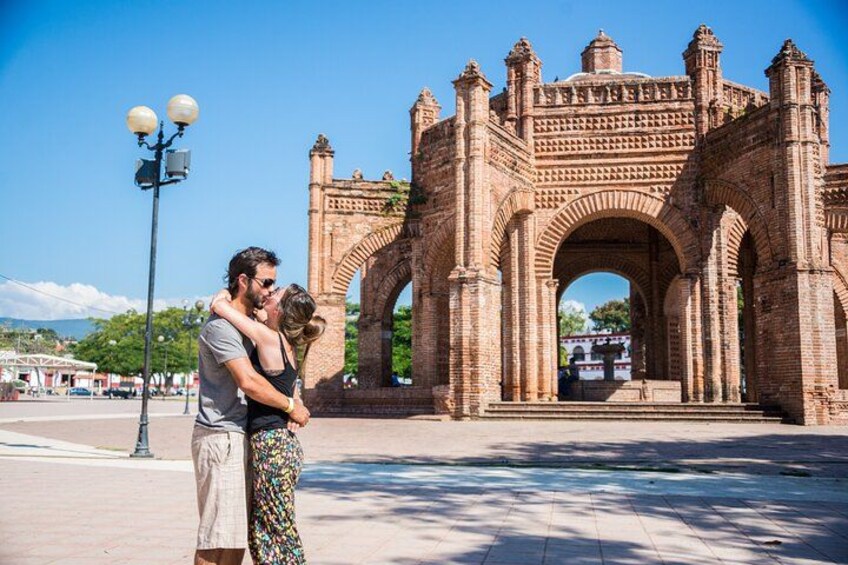 Una pareja se abraza frente a un gran arco de ladrillo decorado. 3