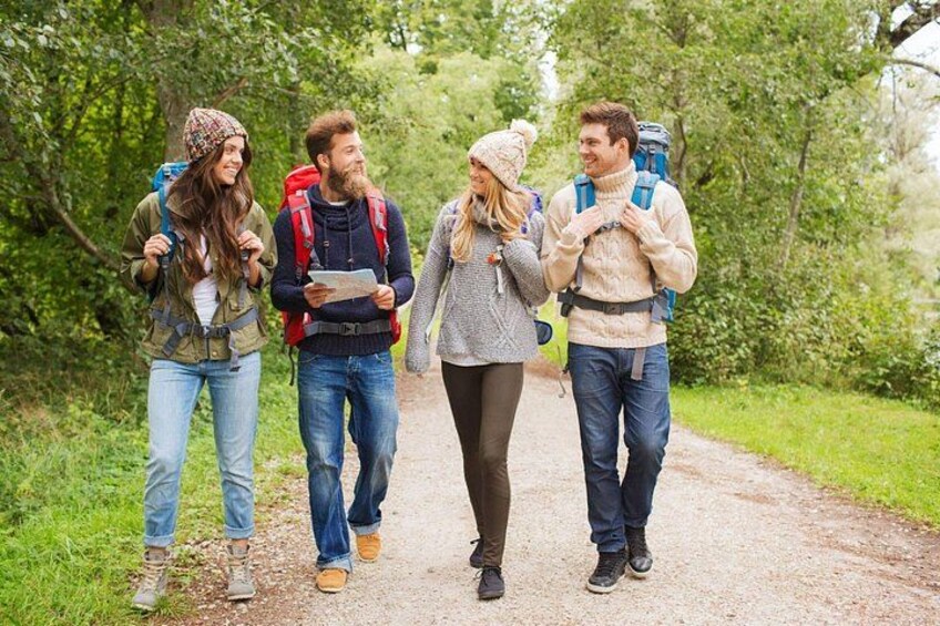 Four people hiking on a dirt path surrounded by greenery. 4
