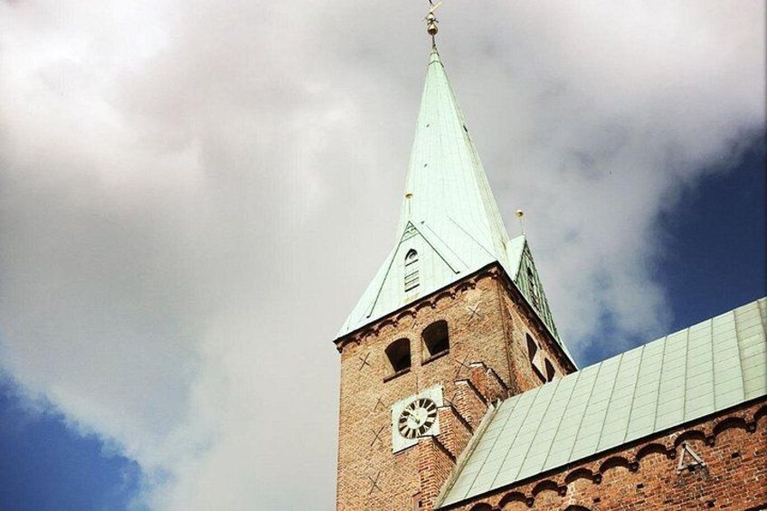 Et kirketårn med et ur under en skyet himmel. 3